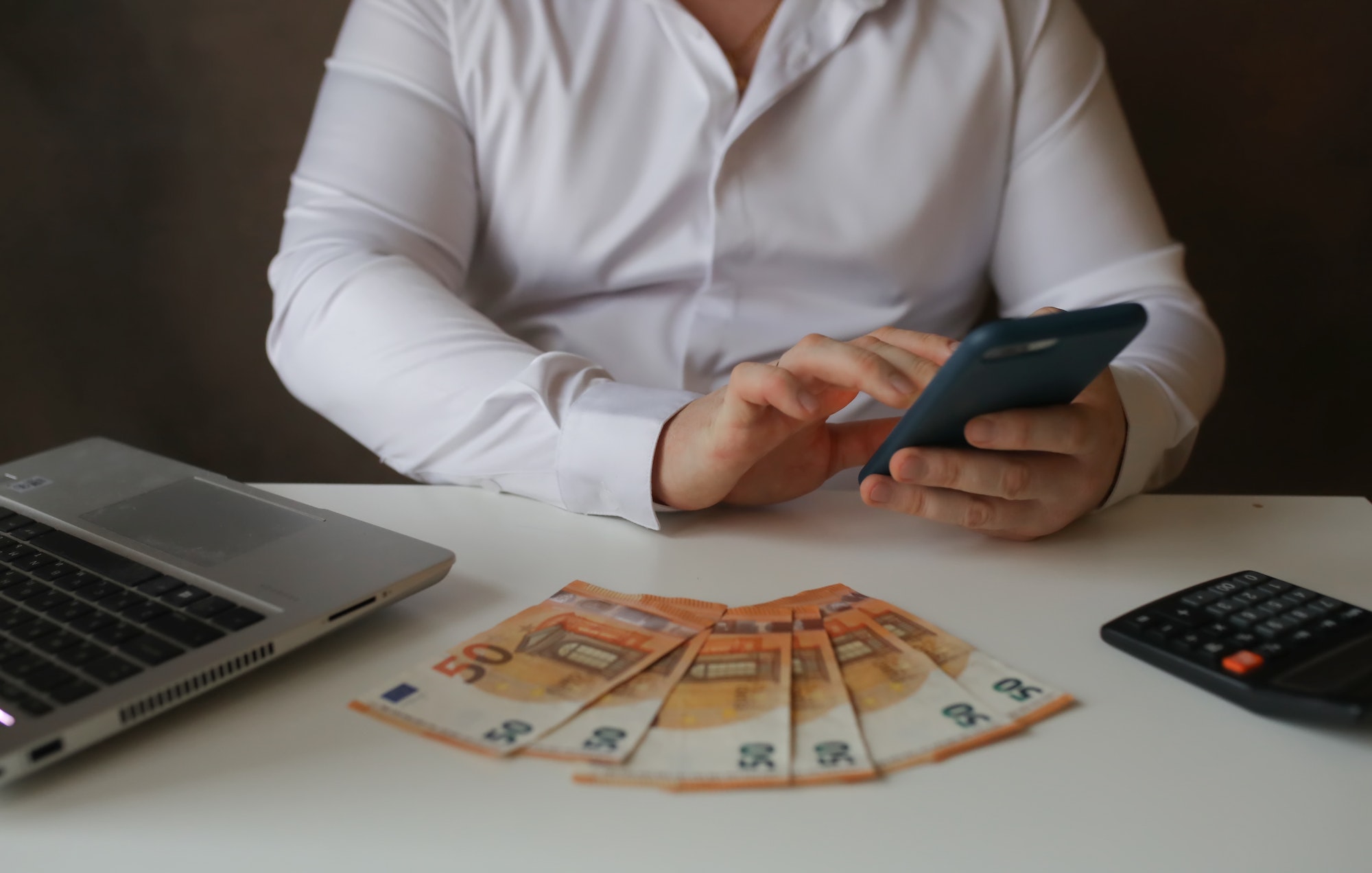 Men’s hands counting money banknotes on mobile phone.