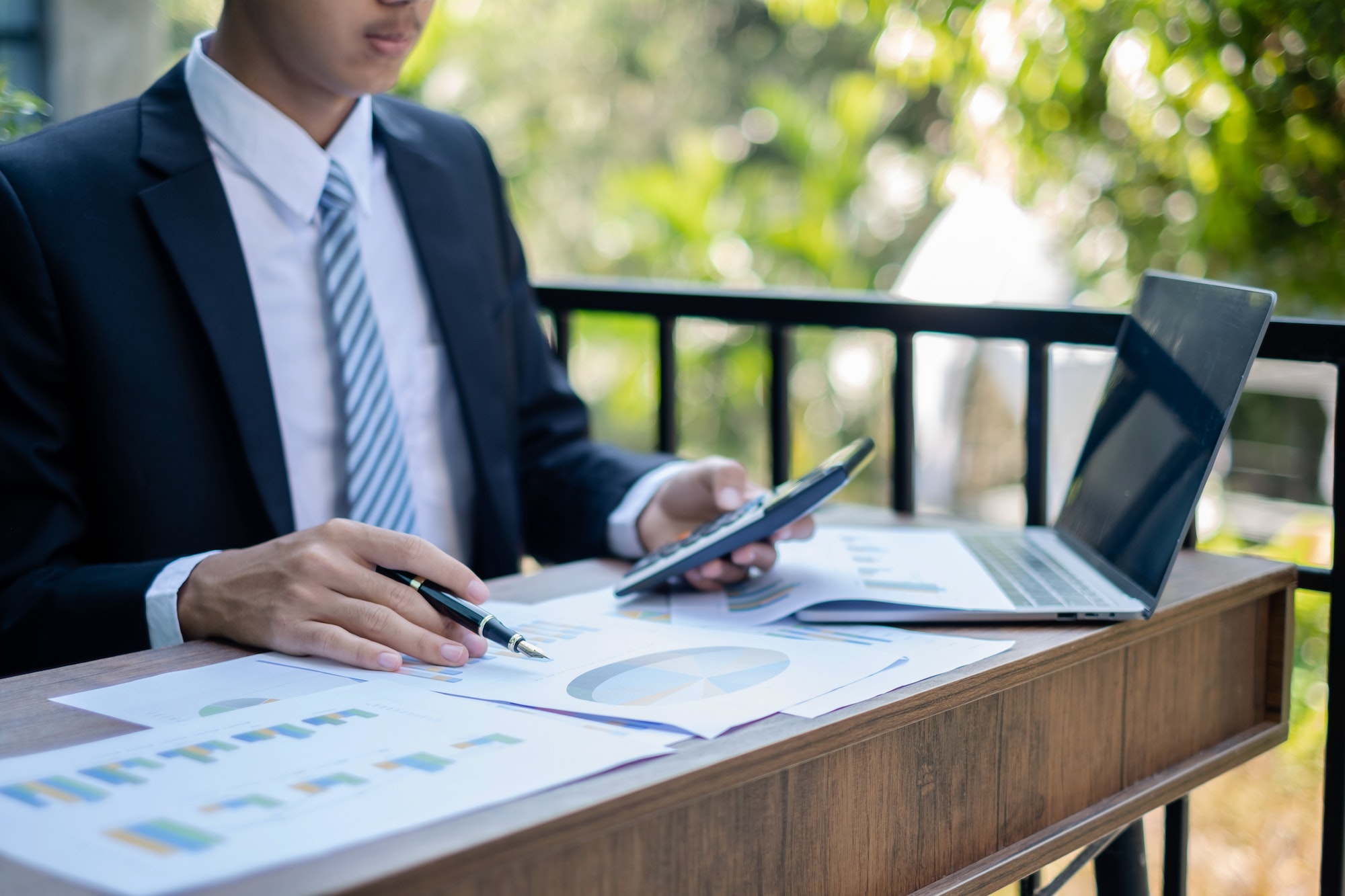 Young Asian businessman financial market analyst sits at their desks and calculate financial graphs
