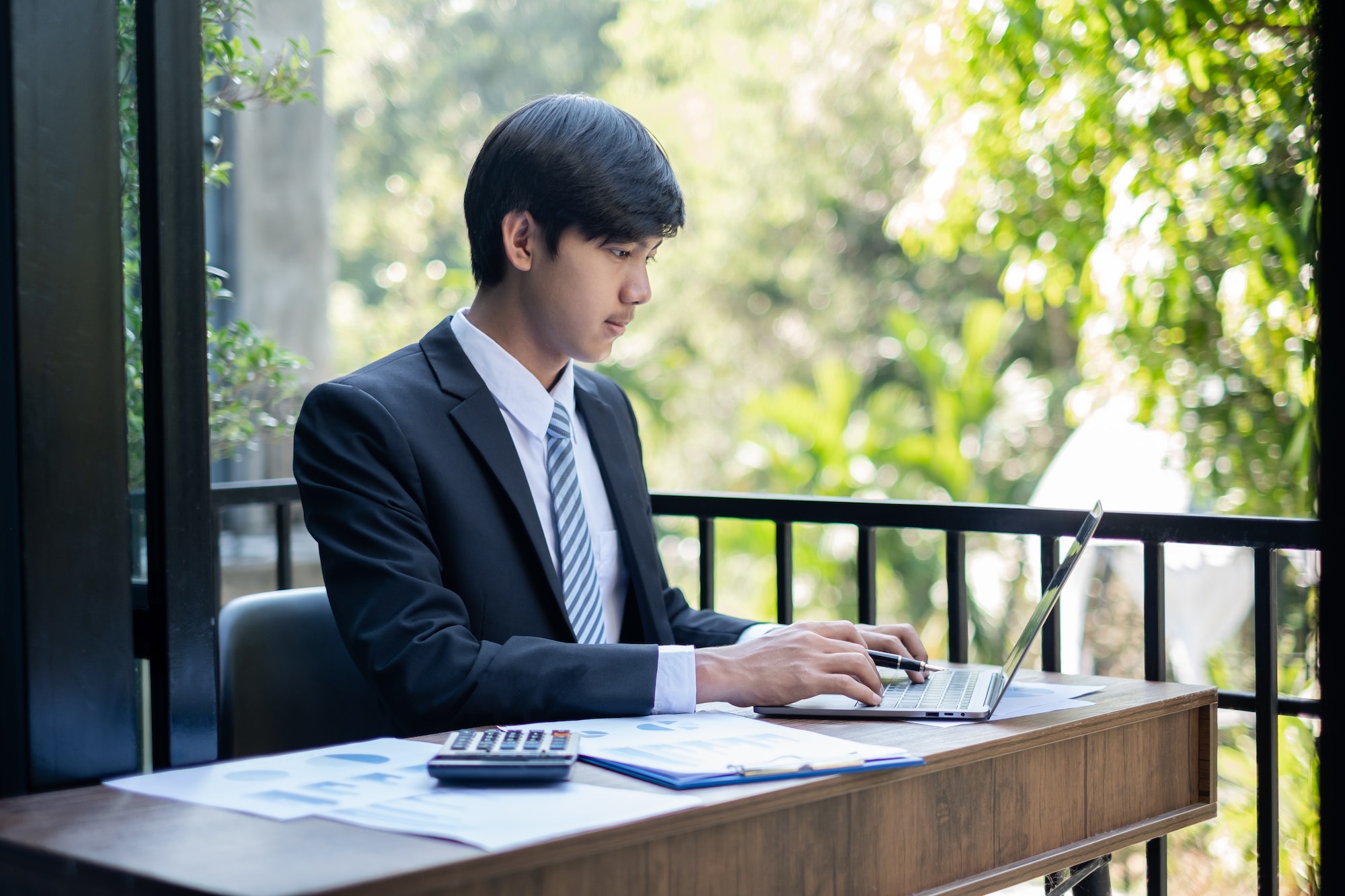 Young Asian businessman financial market analyst sits at their desks and calculate financial graphs